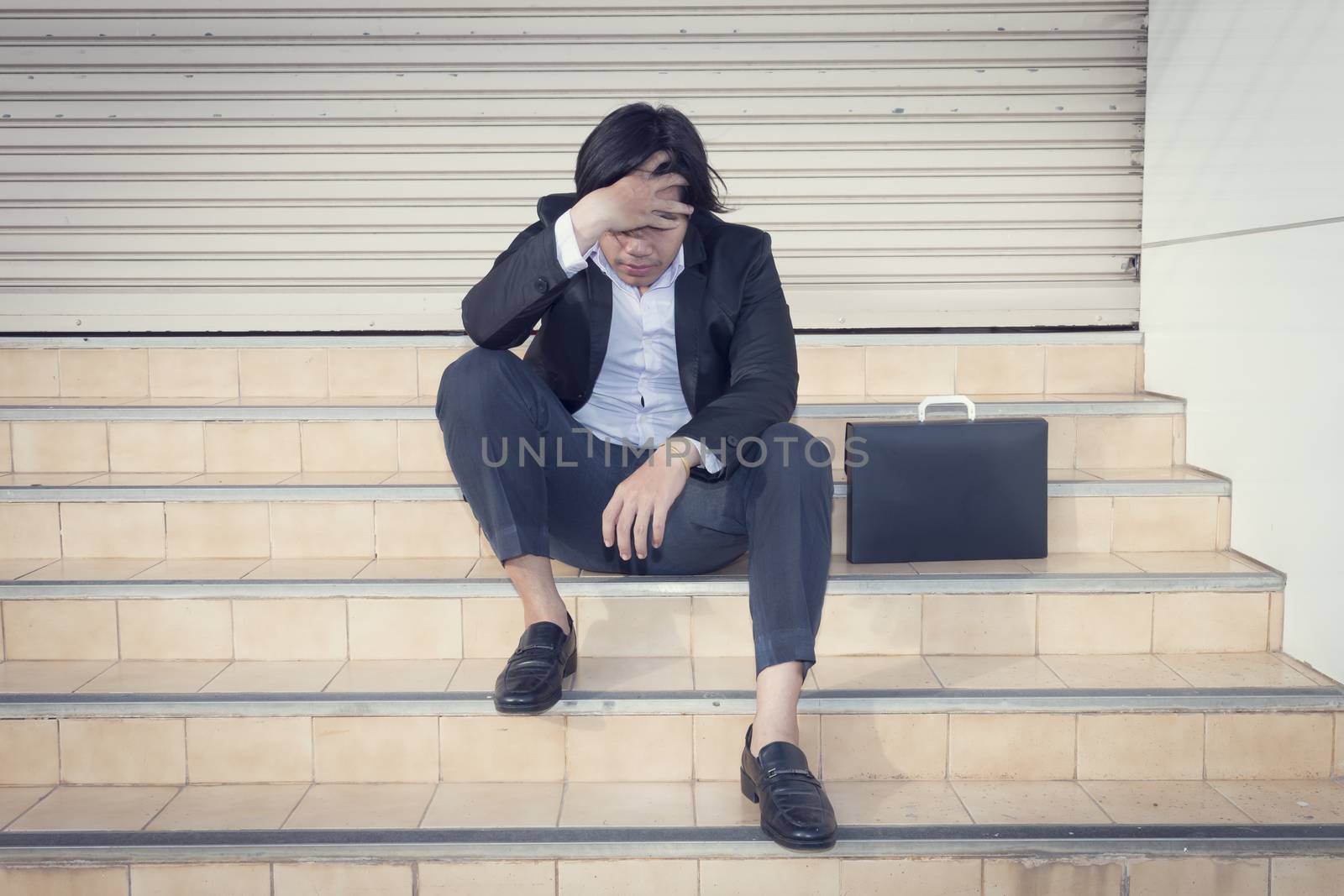 Young depressed businessman sitting on the stairs by Gobba17