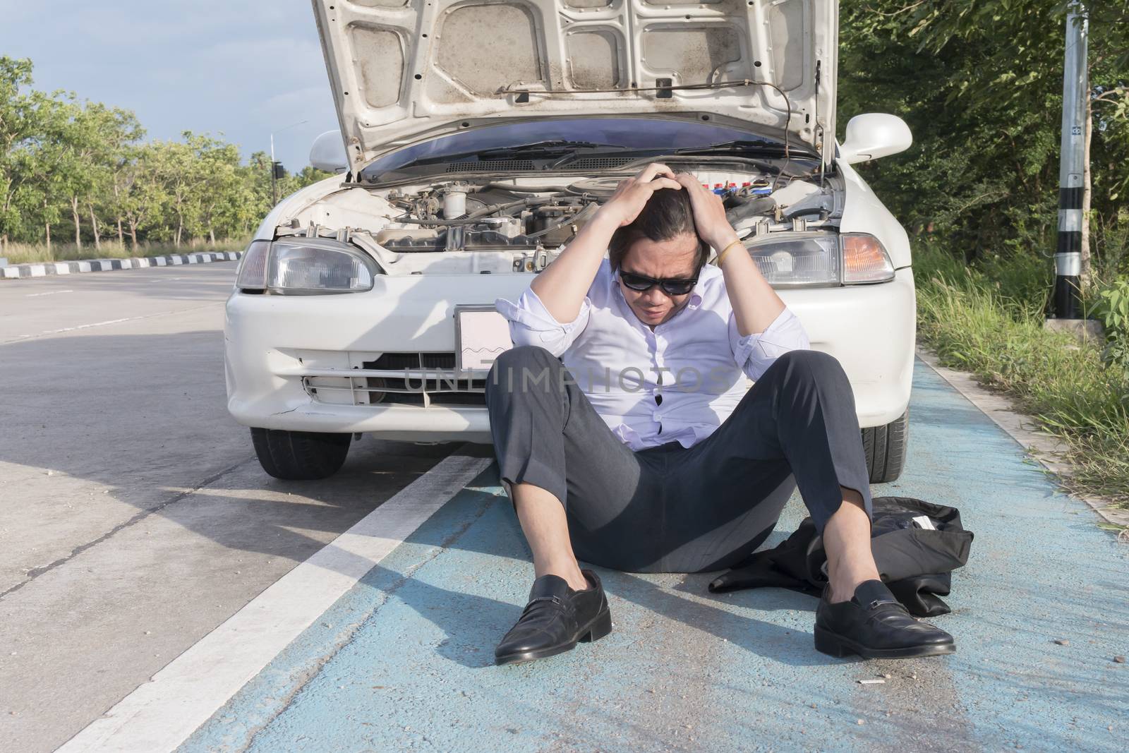 Stress man sitting on a broken car