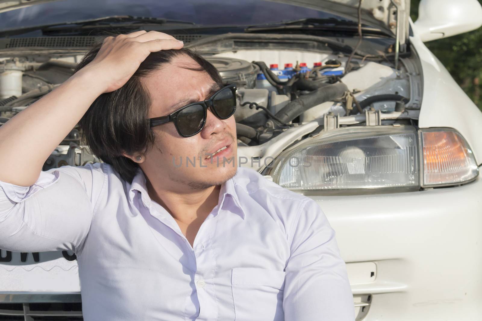 Stress man sitting on a broken car