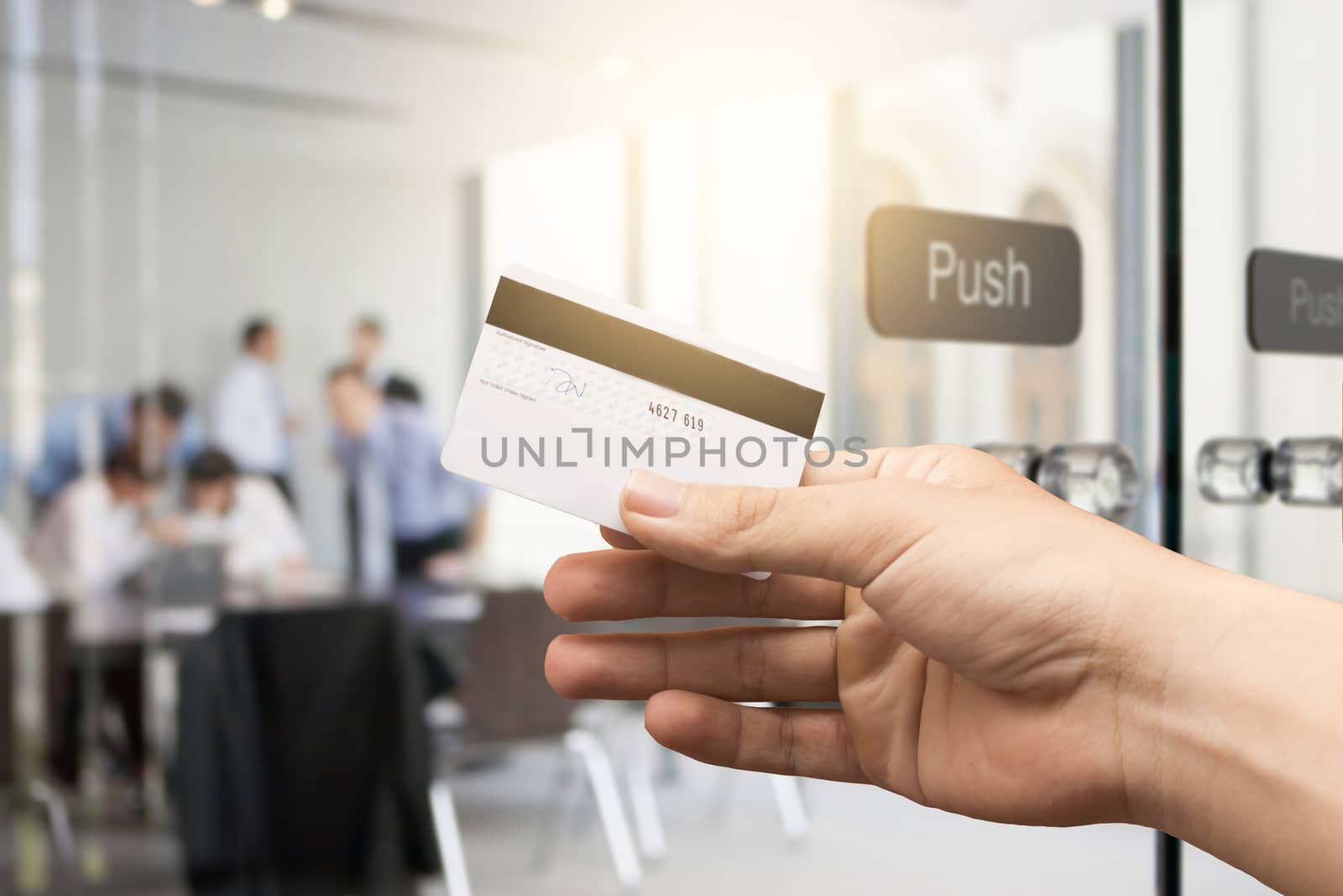 female hand holding credit card against business office background