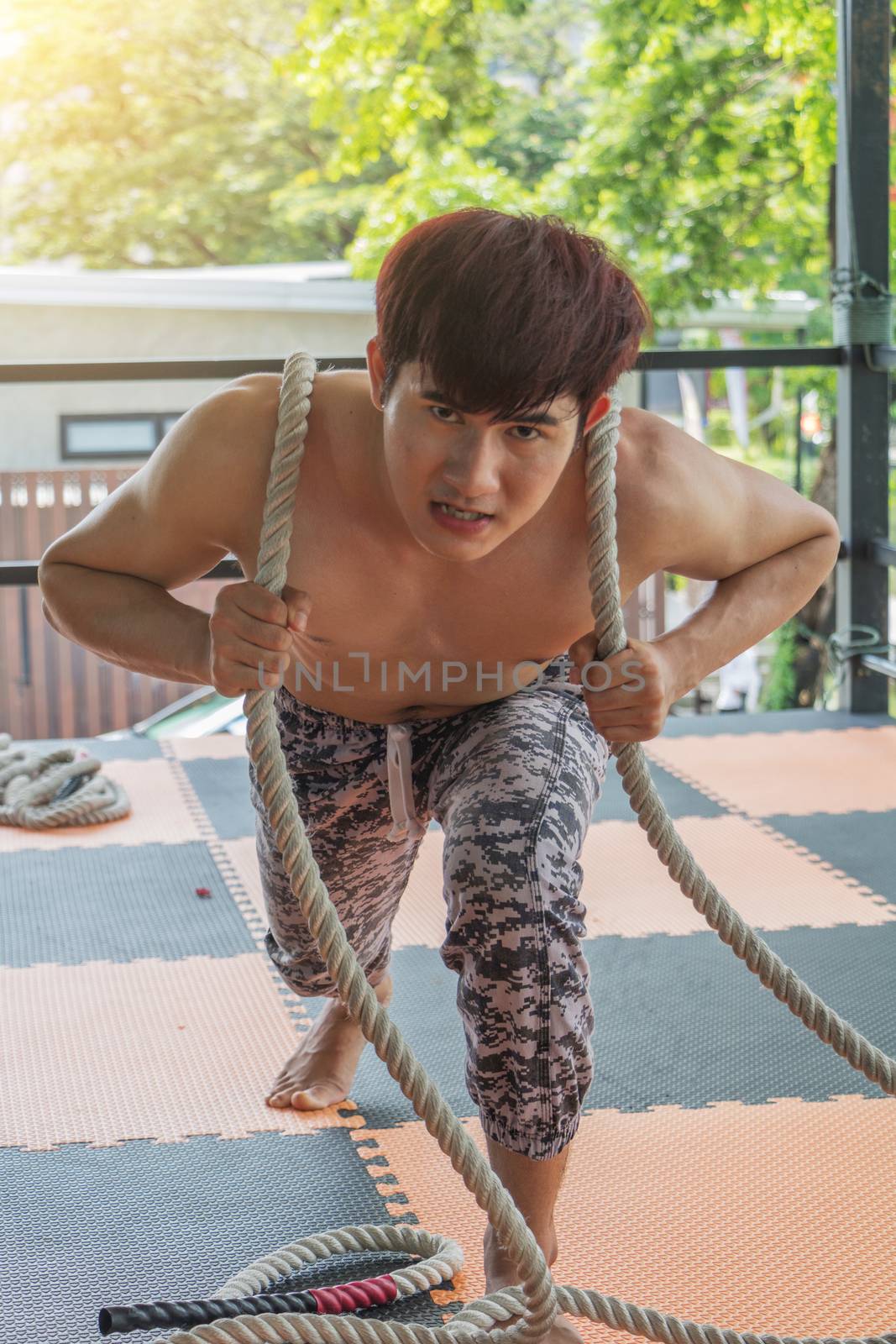 Asian young man is exercising by pulling a rope.