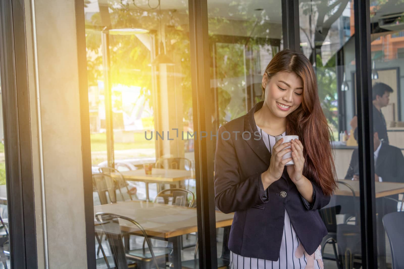 Asian business woman standing to drink coffee, In front of a coffee shop.