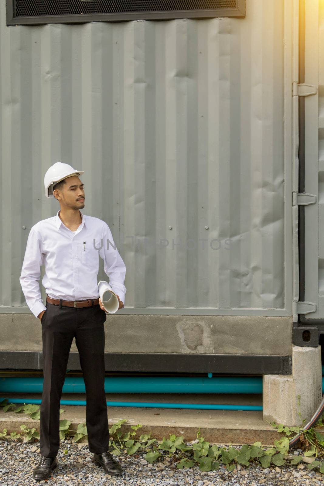 Young Asia man engineer wearing safety white helmet in white shirt checking construction site building.