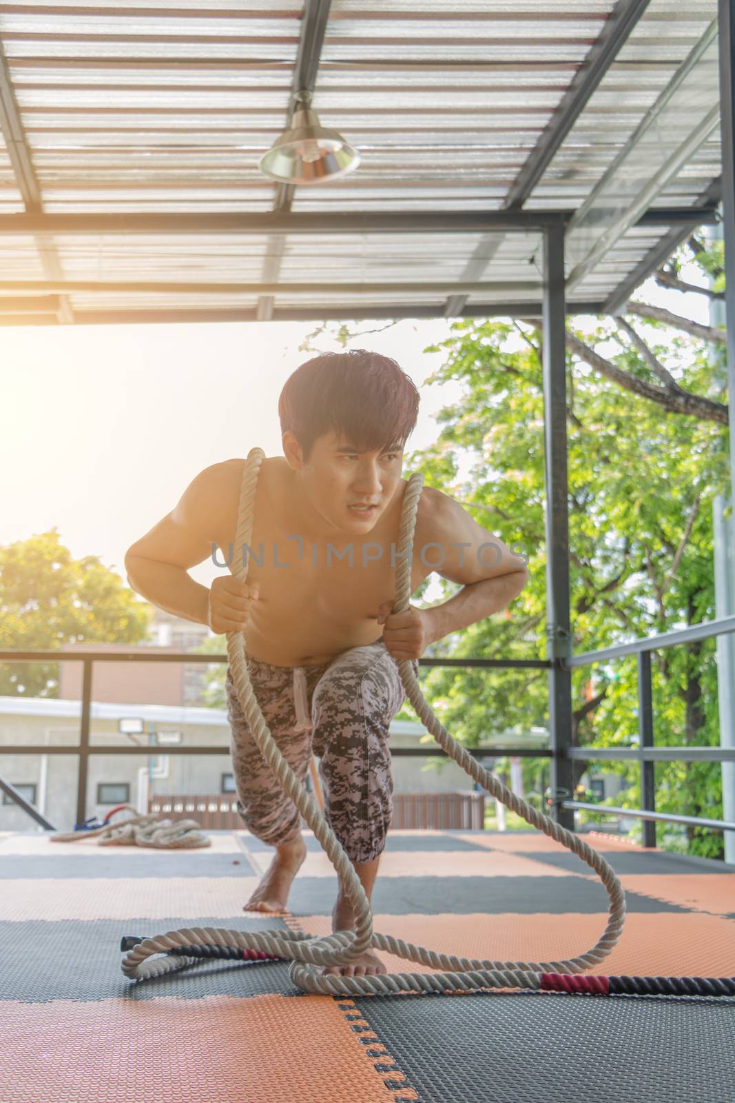 Asian young man is exercising by pulling a rope.