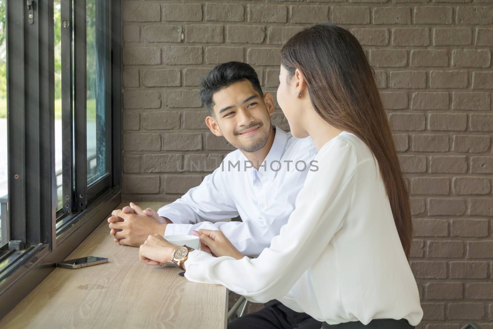 Asian young couple in love at a coffee shop, they are smile. Conception in coffee shop.