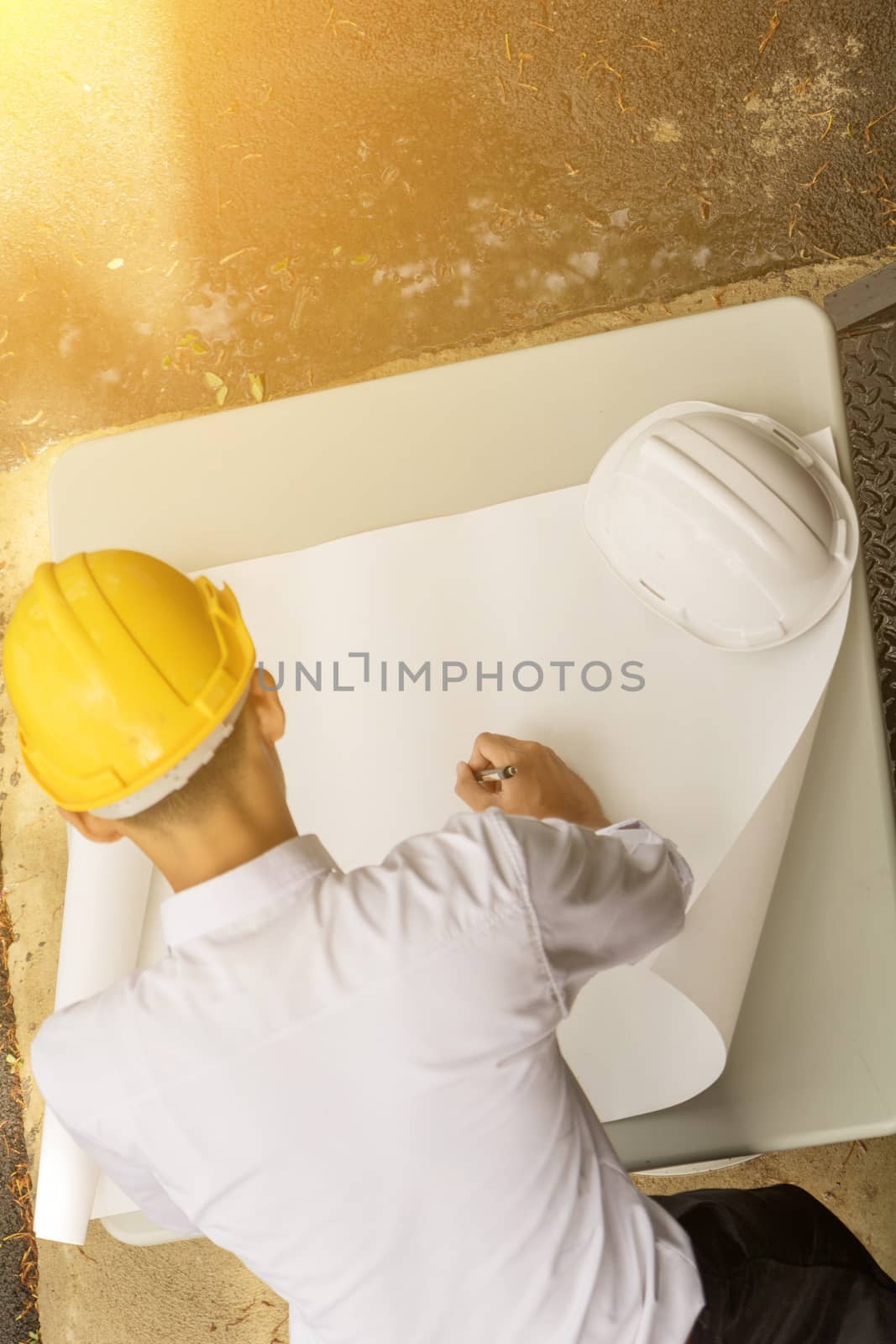 Young Asia man engineer wearing safety yellow helmet in white shirt checking construction site building.