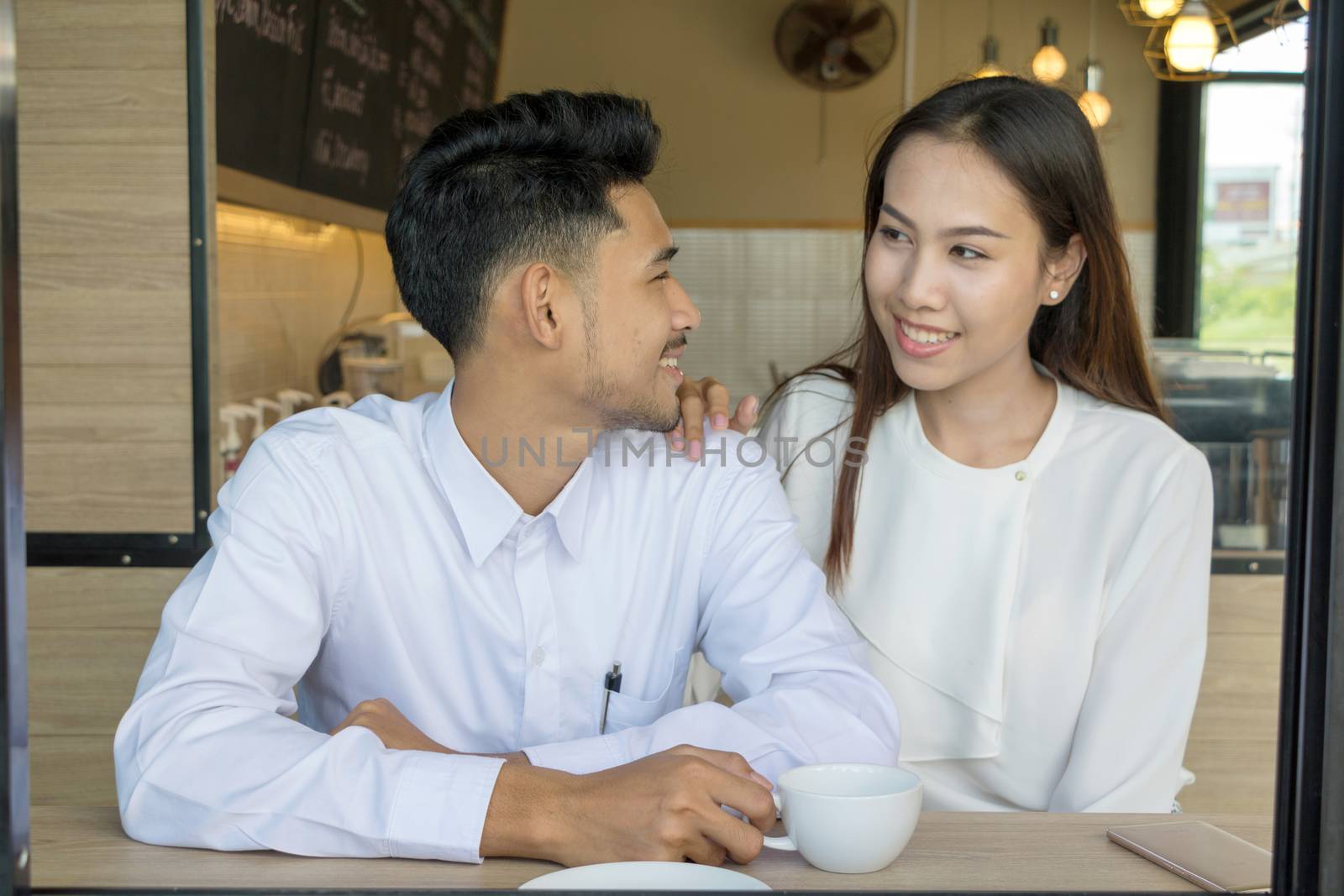 Asian young couple in love at a coffee shop, they are smile. Conception in coffee shop.