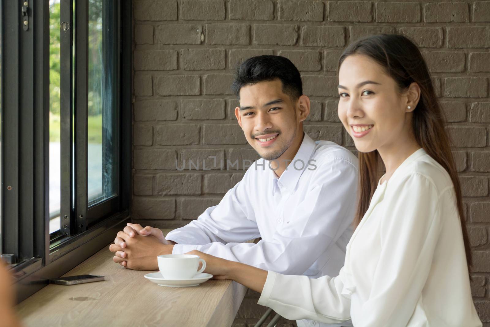 Asian young couple in love at a coffee shop, they are smile. Conception in coffee shop.