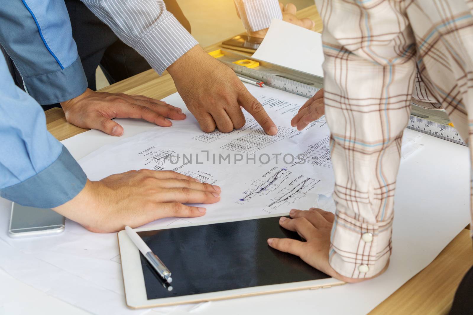 A group of engineers are looking at a blueprint for construction on the table. Engineering concept.