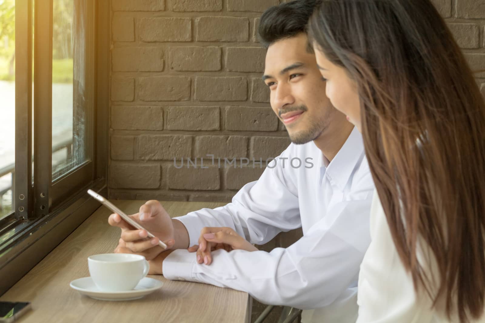 Asian young couple in love at a coffee shop, they are smile. Conception in coffee shop.