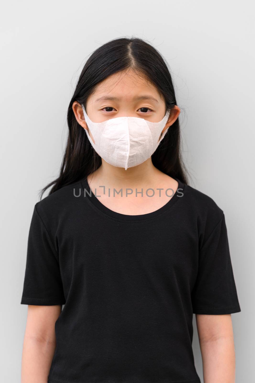 Front view of Asian child wearing mask protecting herself from COVID-19 or Corona Virus.