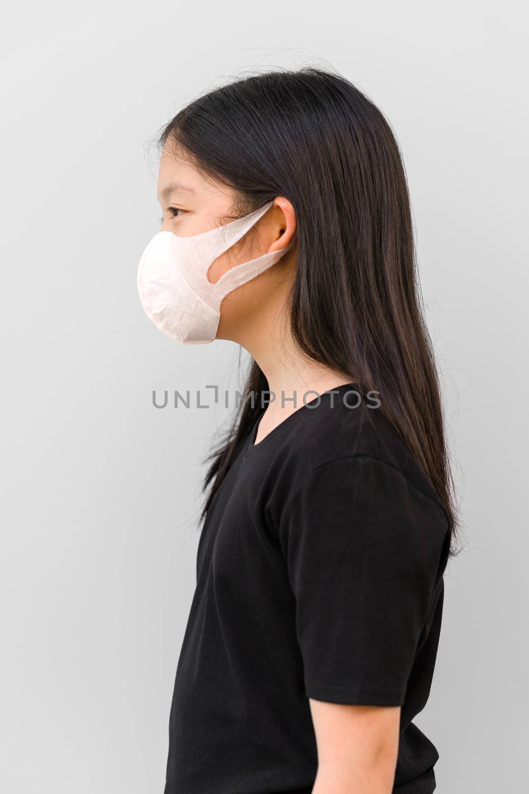 Side view of Asian kid wearing mask protecting herself from COVID-19 or Corona Virus.