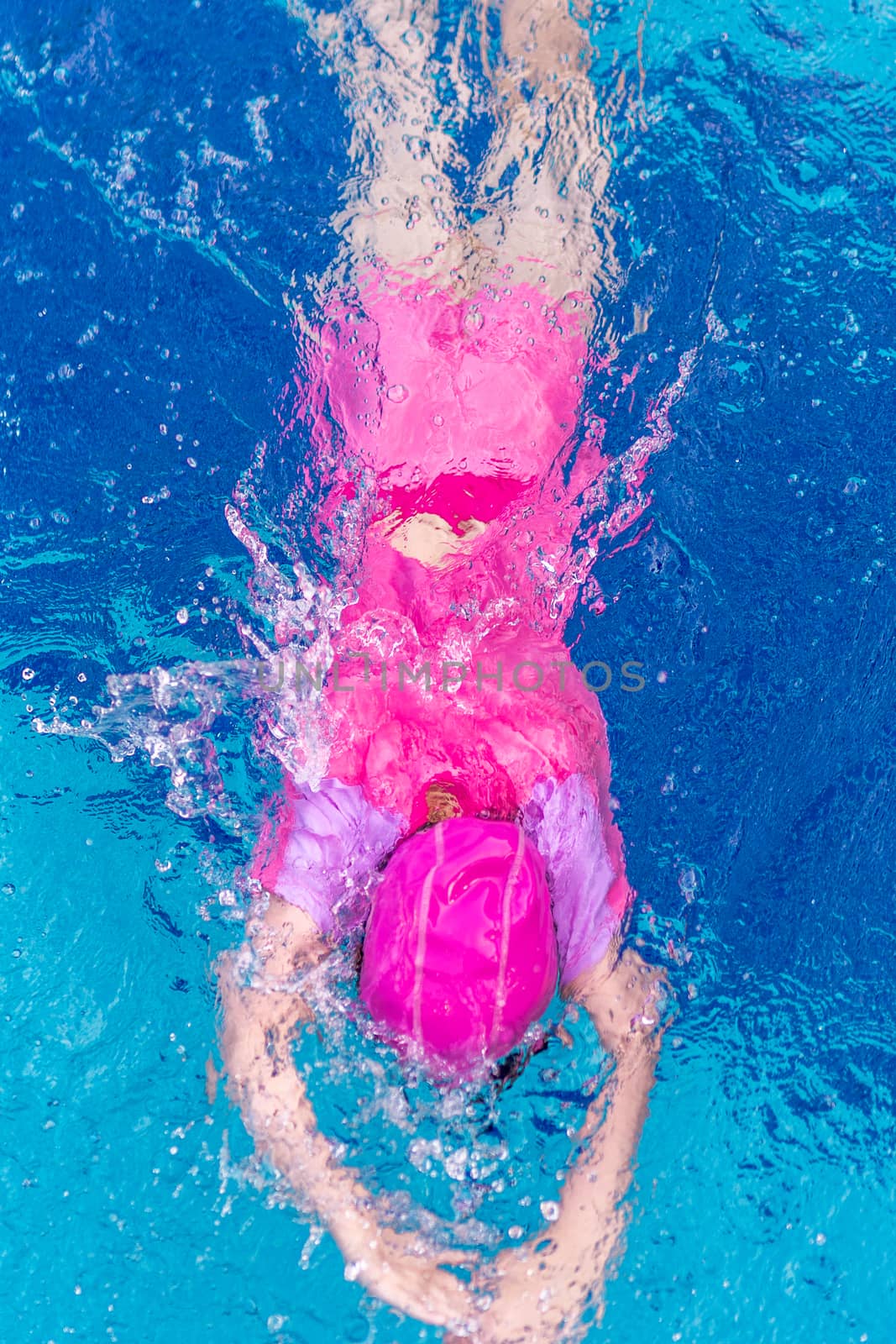 Child or kid swimming in swimming pool from top view.