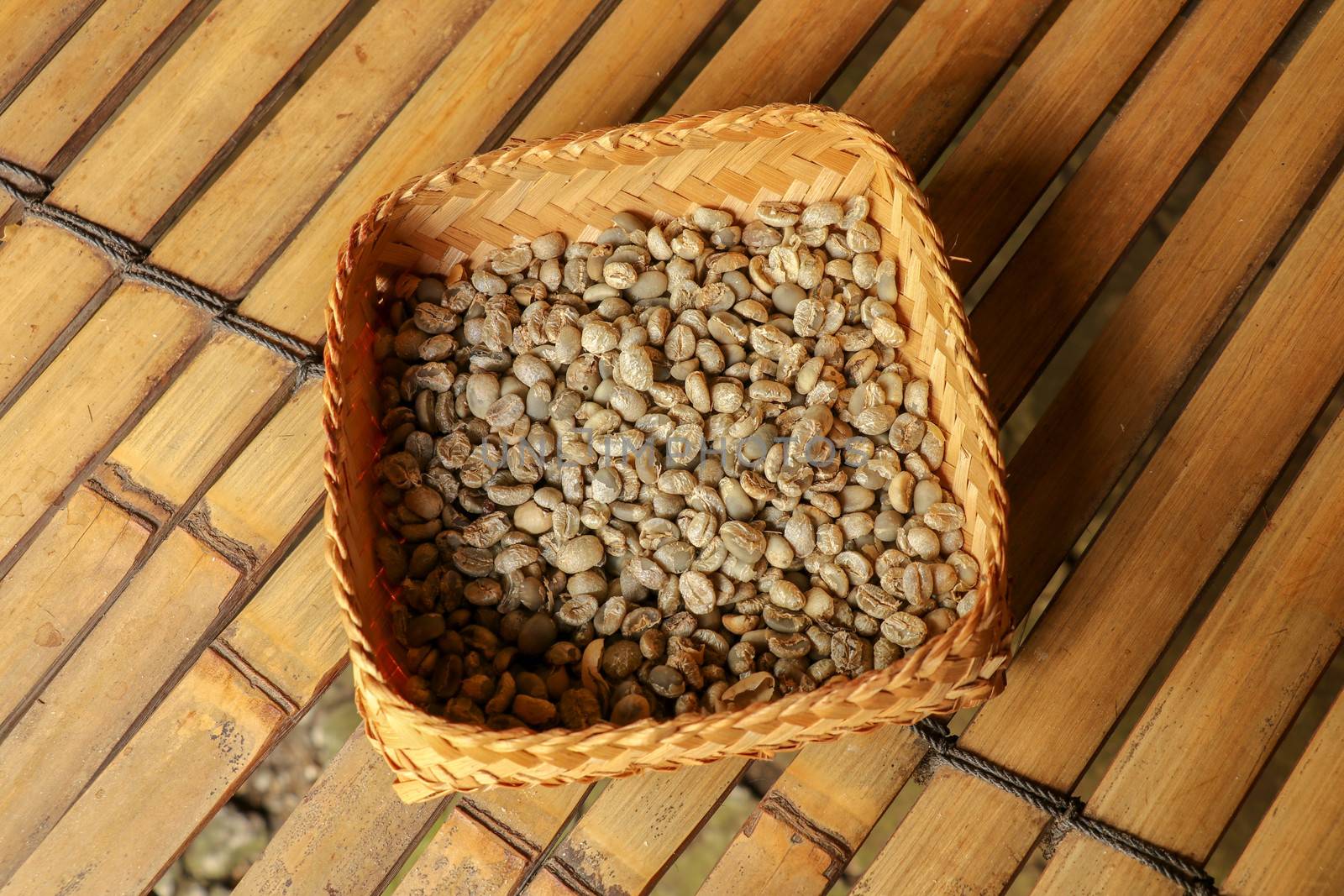 Wicker robe made of bamboo strips filled with fresh Arabica coffee beans. Close up of natural process of coffee beans drying on coffee factory in Bali. Dried coffee beans ready for roasting process.