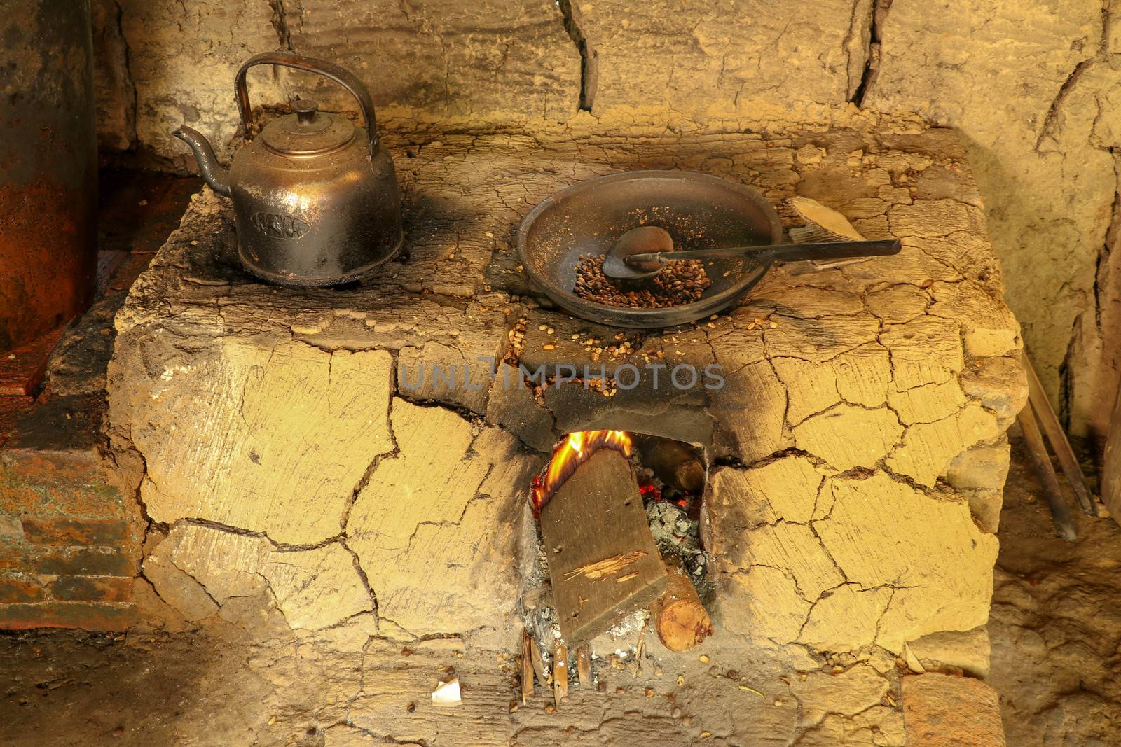 Traditional clay furnace with open fireplace. Primitive way of roasting coffee beans in steel pan at coffee farm in Bali, Indonesia. Simple production of coffee Arabica, Kopi Luwak on coffee factory.