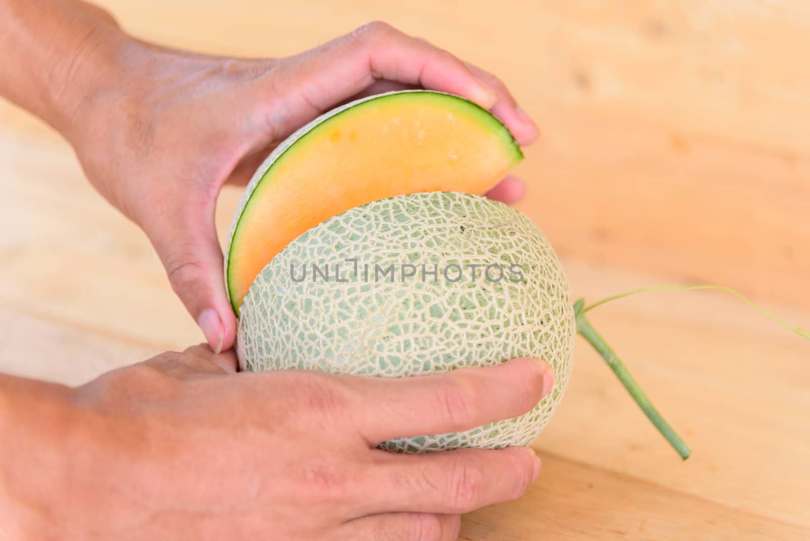 The man use knife split the orange melon on wood plate by rukawajung
