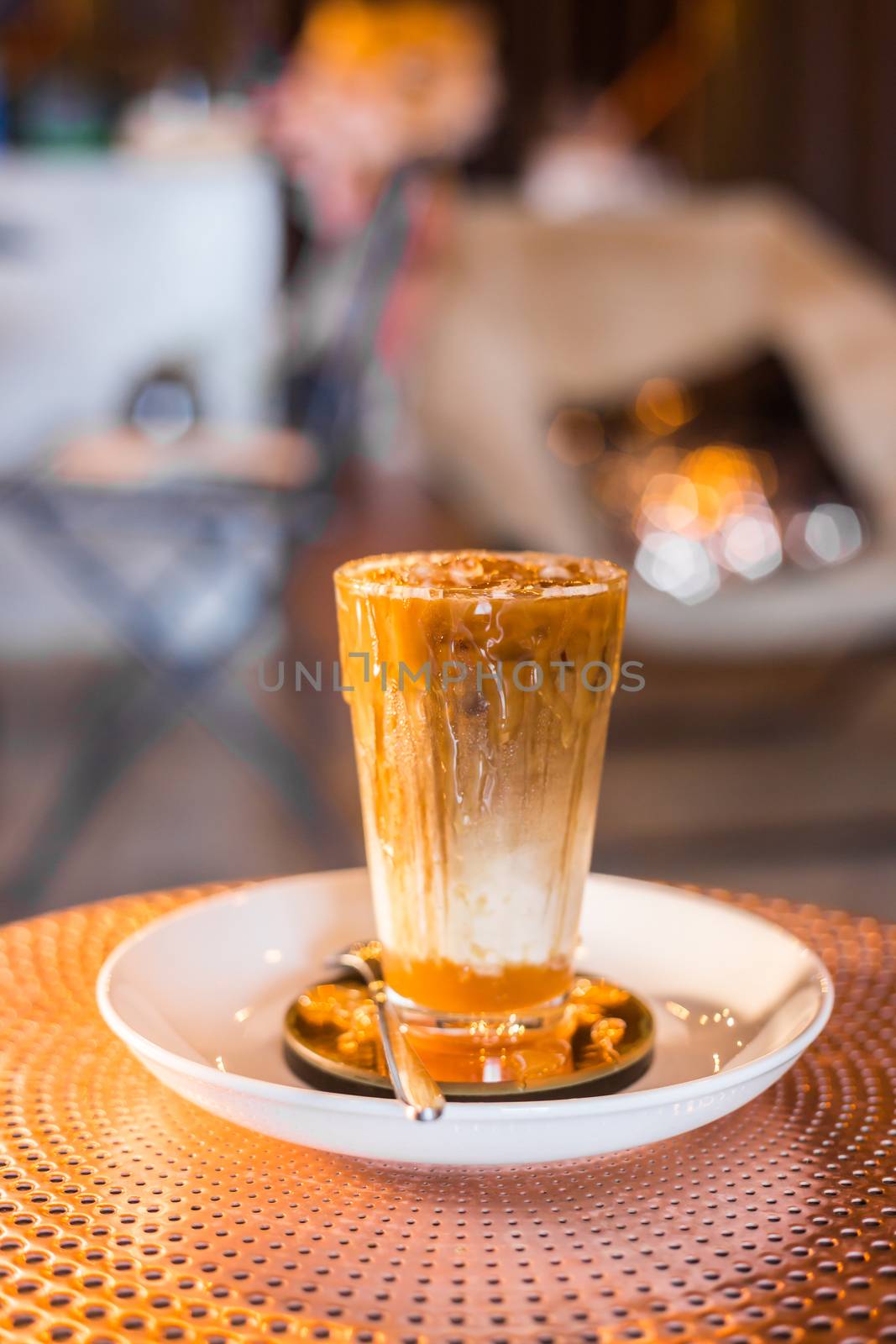 Iced coffee with milk in tall glasses on the table with caramel syrup.