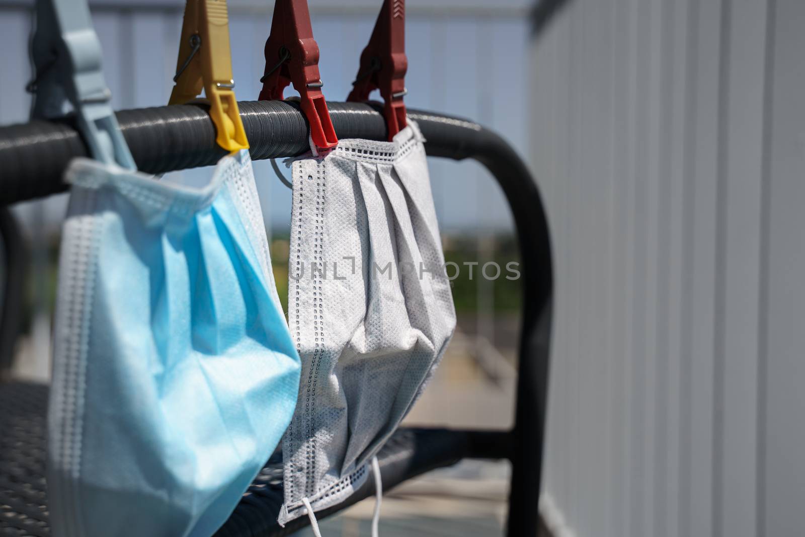 Surgical face mask for coronavirus hanging on clothesline string with clothespin. Reuse of these masks can minimize waste, protect the environment, and help to solve the current imminent shortage of masks.