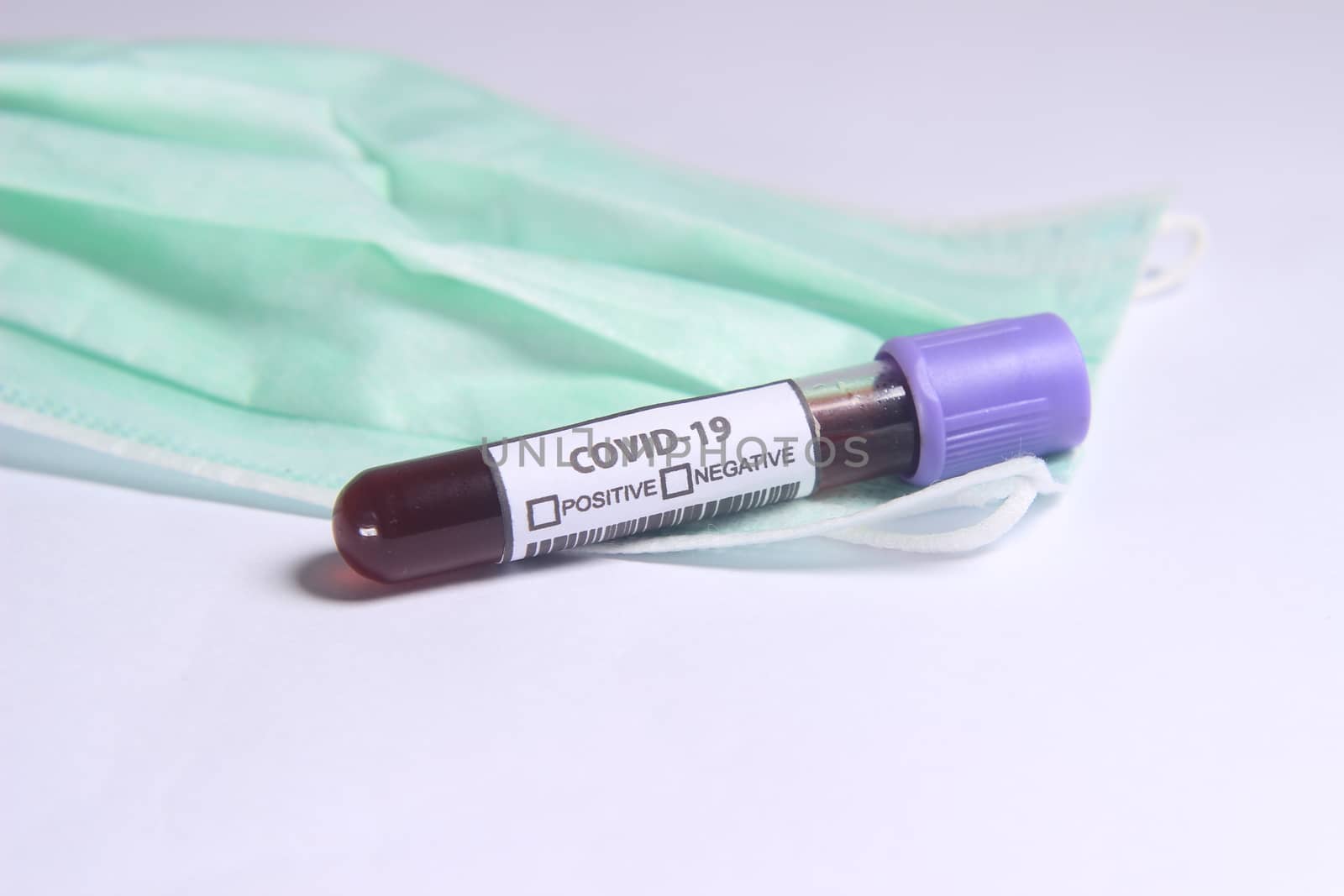 Close Up Photo, Simple Conceptual, Glass Blood Covid-19 Test tube, above N95 Surgical Mask by tutik