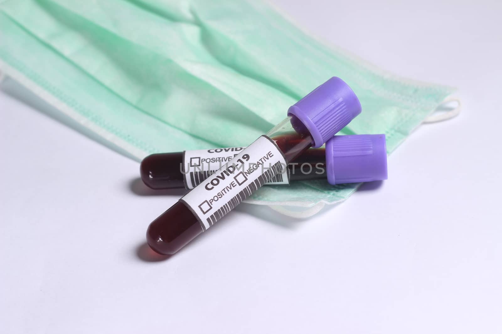 Close Up Photo, Simple Conceptual, Glass Blood Covid-19 Test tube, above N95 Surgical Mask by tutik