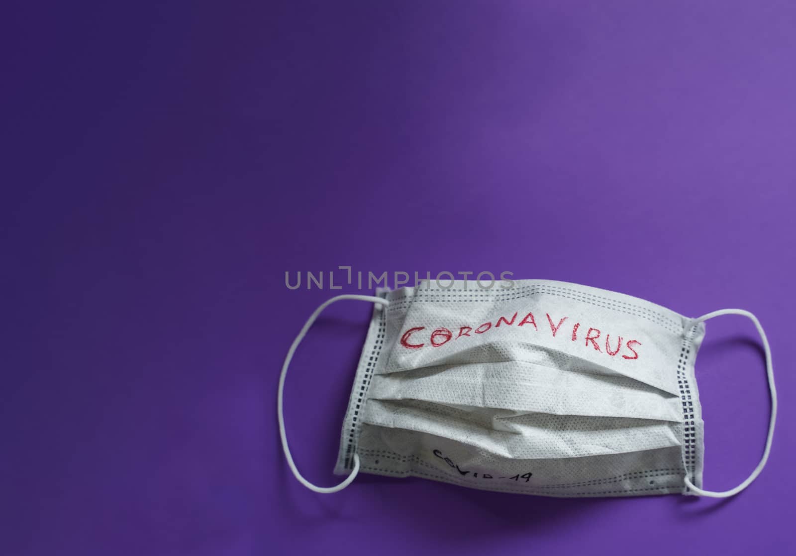 White medical mask with coronavirus word on it isolated on purple background. Face mask protection against pollution, virus, flu and coronavirus. Health care and surgical concept.