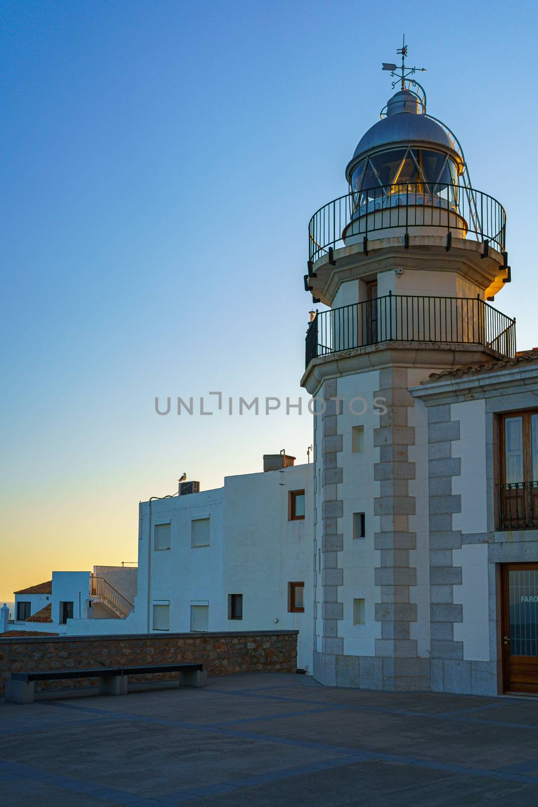 white lighthouse at sunset in the medieval and mediterranean town of Peniscola, Spain.