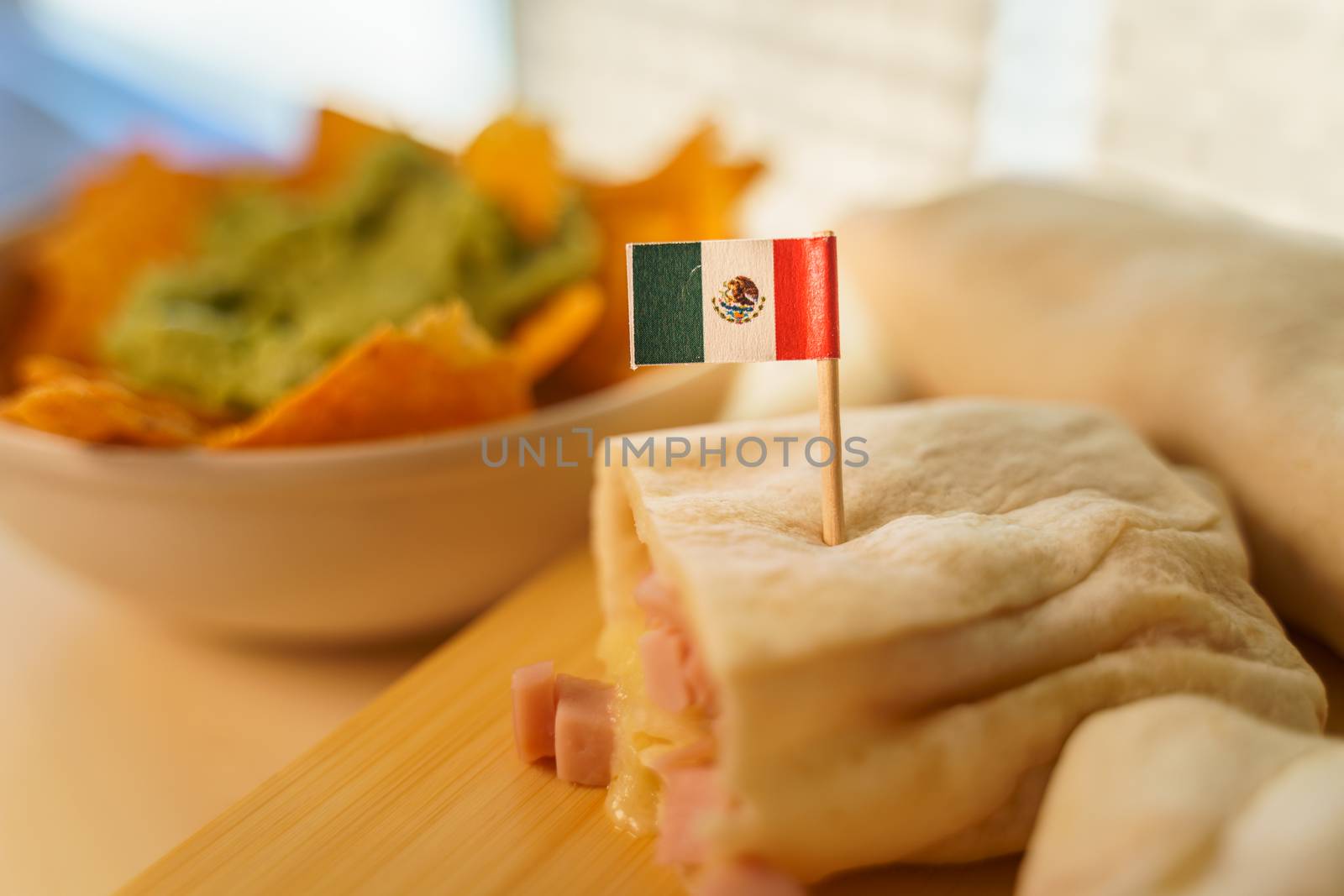 Close up of a hot fresh burrito and nachos with guacamole cream. The first Thursday in April of every year is the National Burrito day