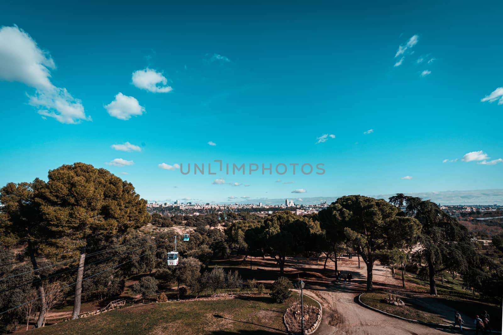 Cable car over casa de campo park and Madrid skyline on the Background. Teal and orange graded.