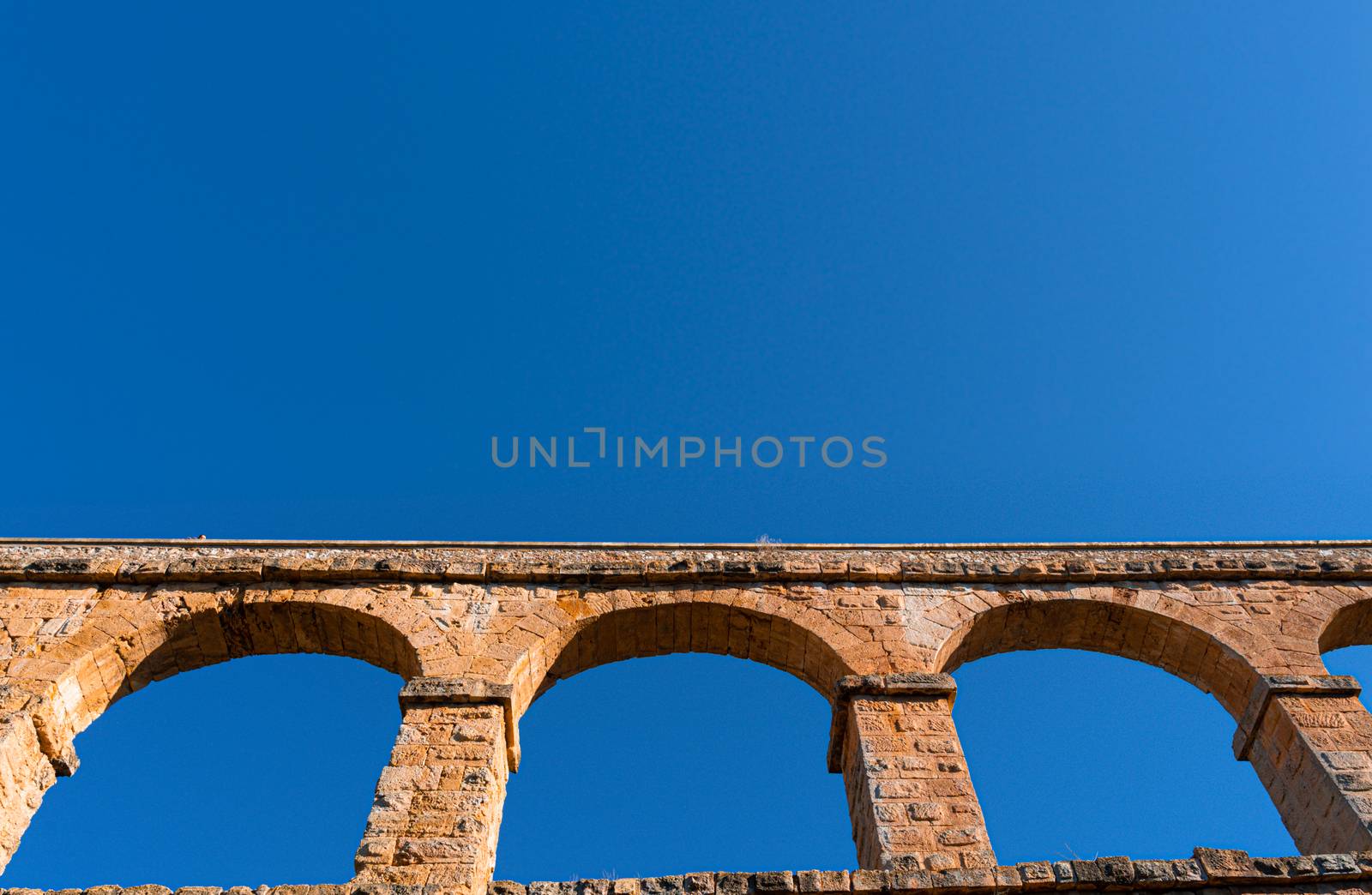 Teal and orange view of a roman aqueduct with copy space available by tanaonte