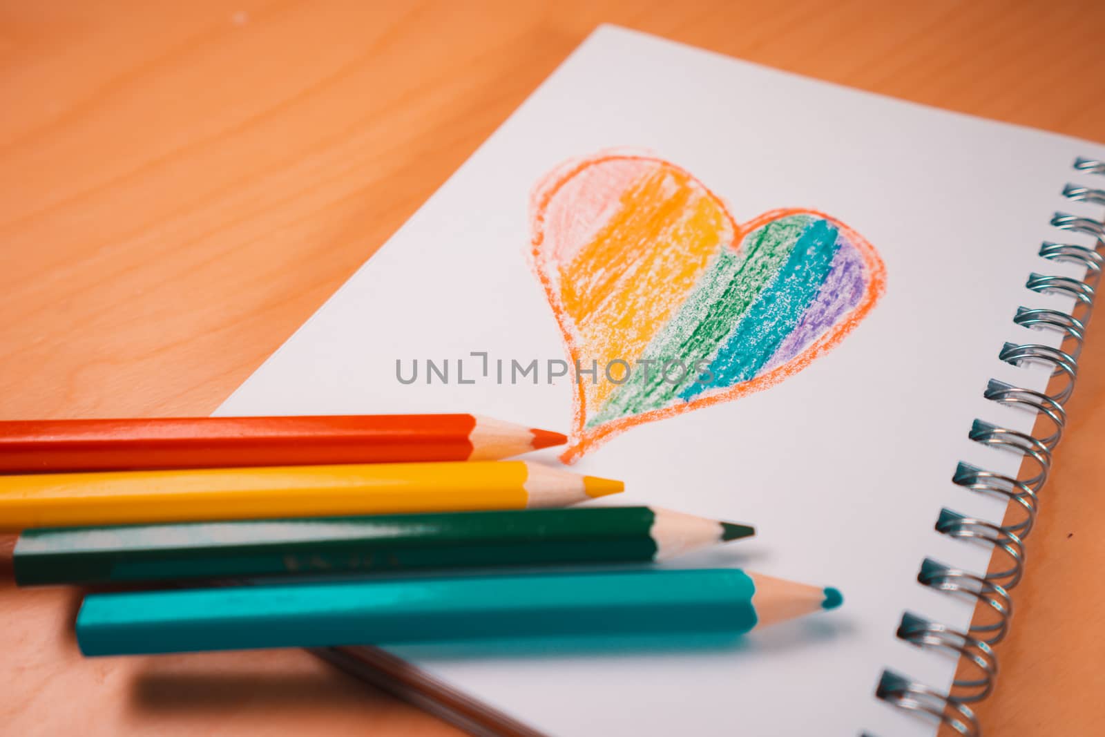 Heart with the colors of the LGTBI or GLBT flag on a blank notebook with rainbow pens. Copy space to add some text or graphics