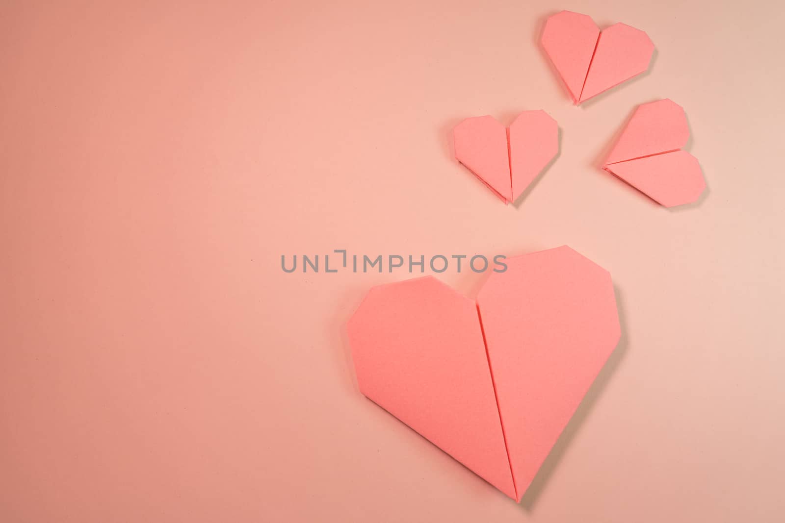 Pink origami hearts on a pink background. Paper craft, suitable for love, Valentine Day, romance and wedding concepts with copy space available.