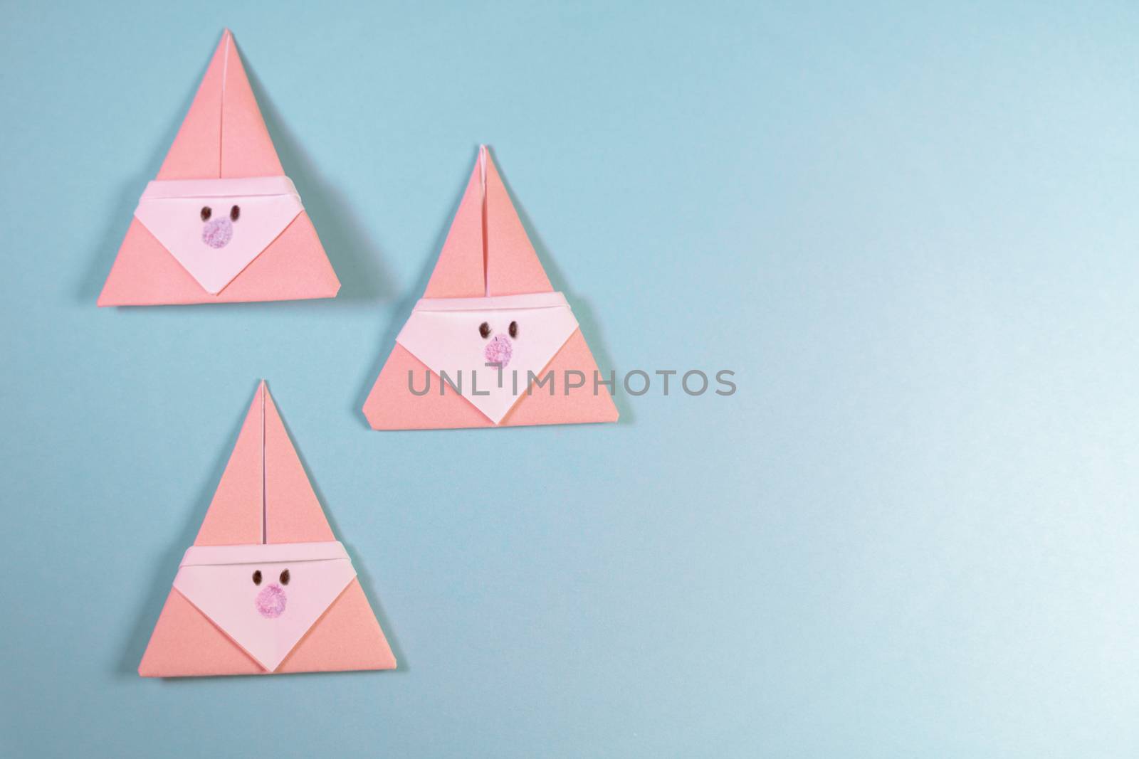 Three Origami Xmas Santa claus on a blue background by tanaonte