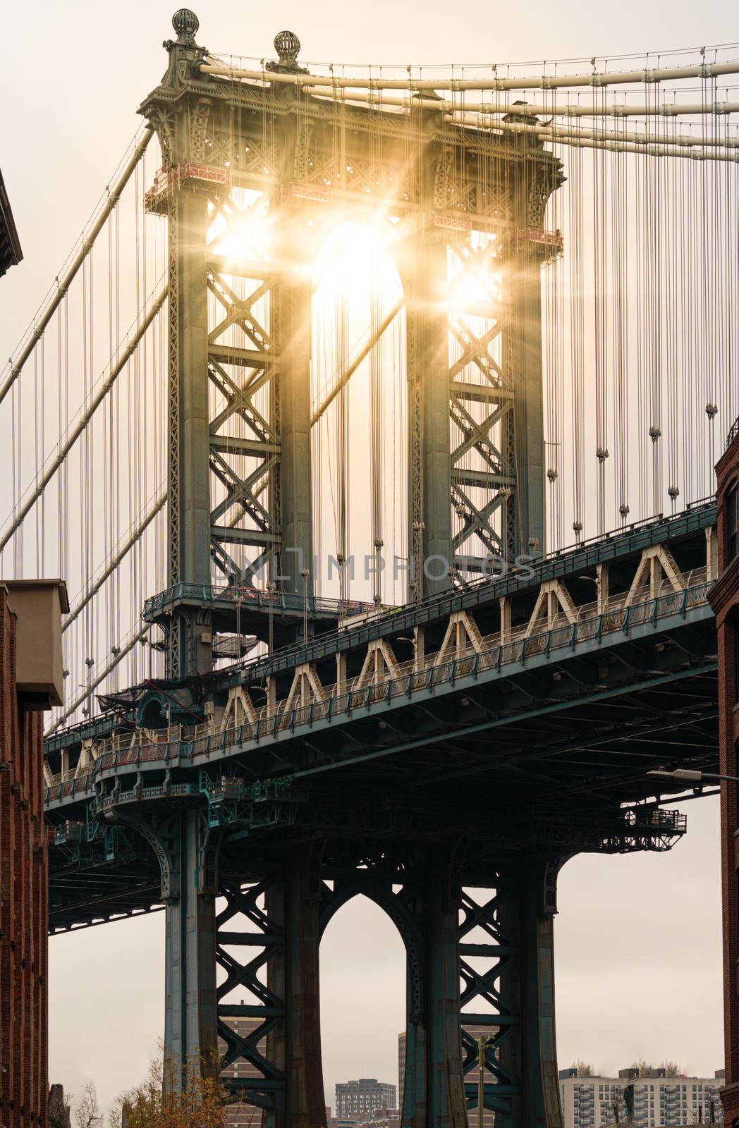 Sun beams through a pillar of Manhattan Bridge as seen from Dumbo district in Brooklyn by tanaonte