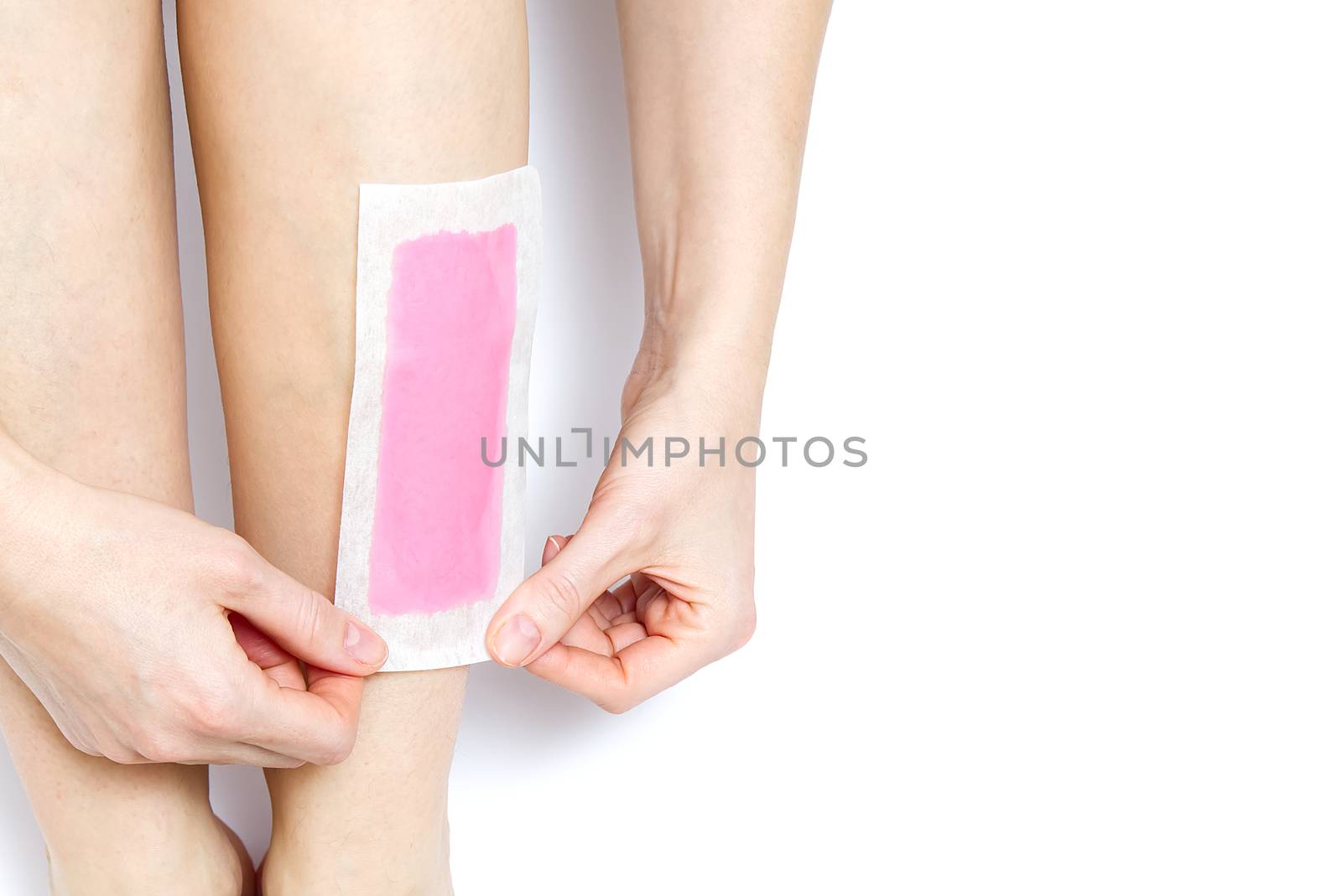 Beautiful woman doing depilation for her legs with waxing, isolated on white. Woman using pink wax strips.