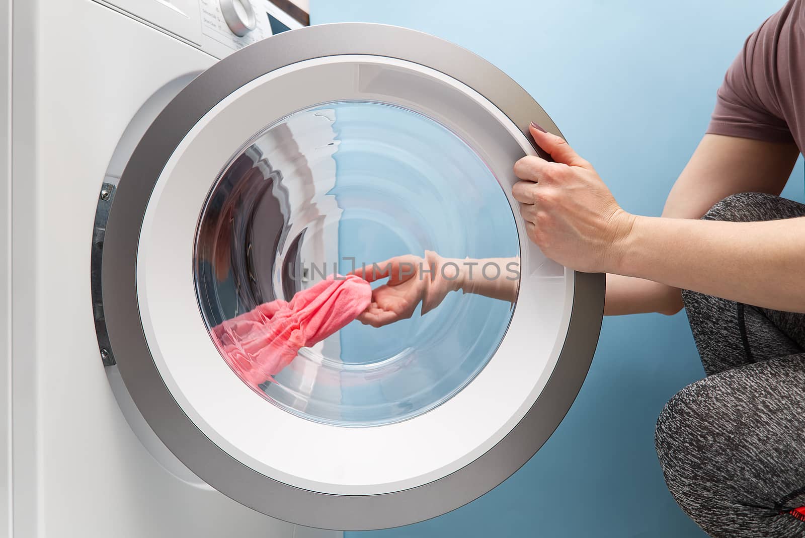 girl takes out the laundry from the washing machine. woman puts clothes in a washing machine by PhotoTime