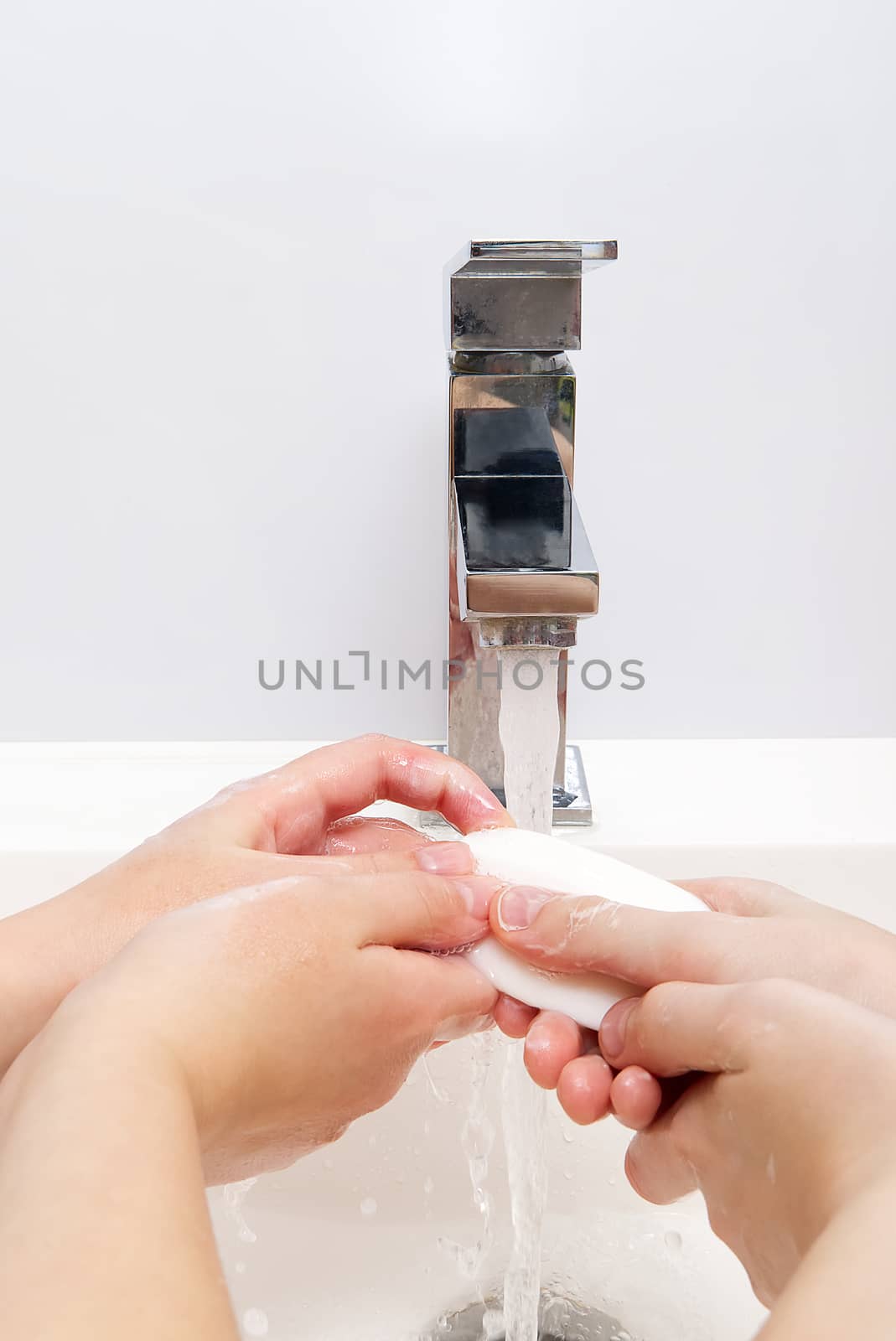 Childrens washing hands with soap under the crane with water. close-up. personal hygiene concept by PhotoTime
