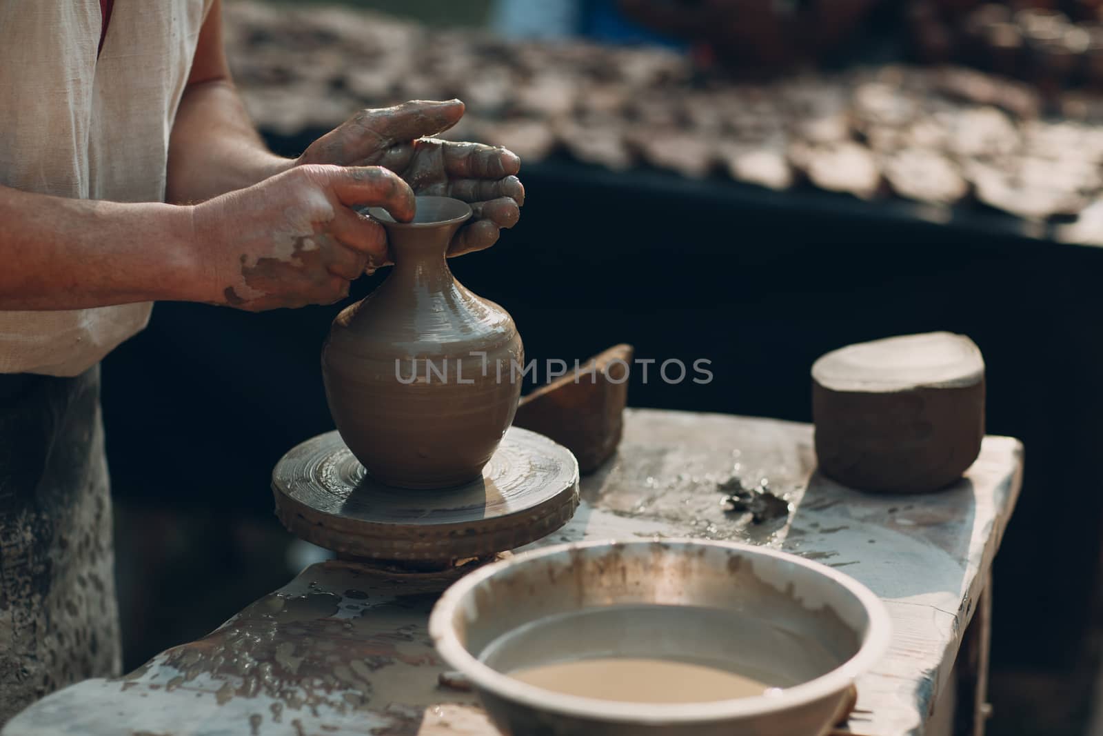 Potter makes clay pot jar on potter's wheel by primipil