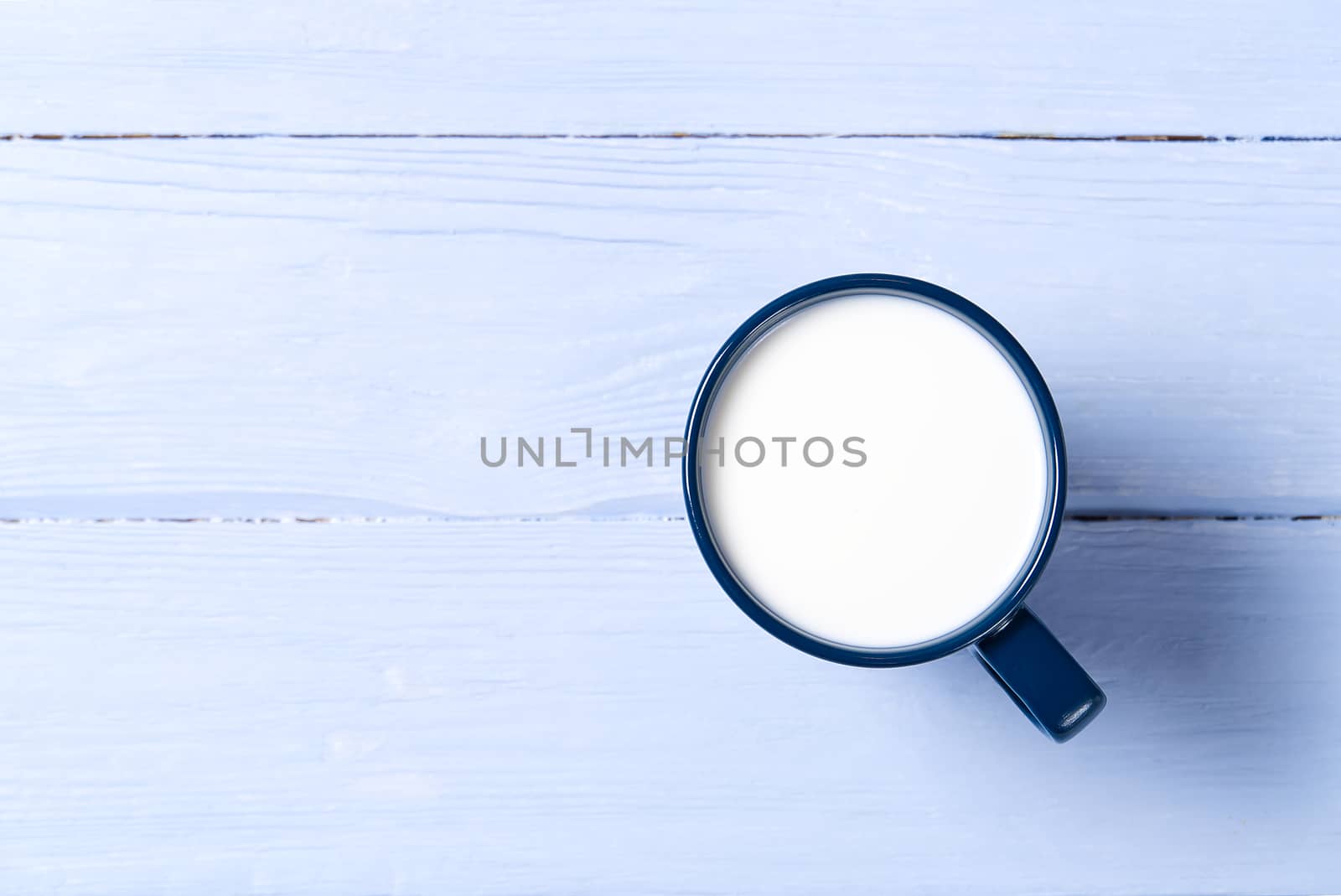 Blue cup of milk on light blue wooden background. view from above - flat lay. Blue mug with milk