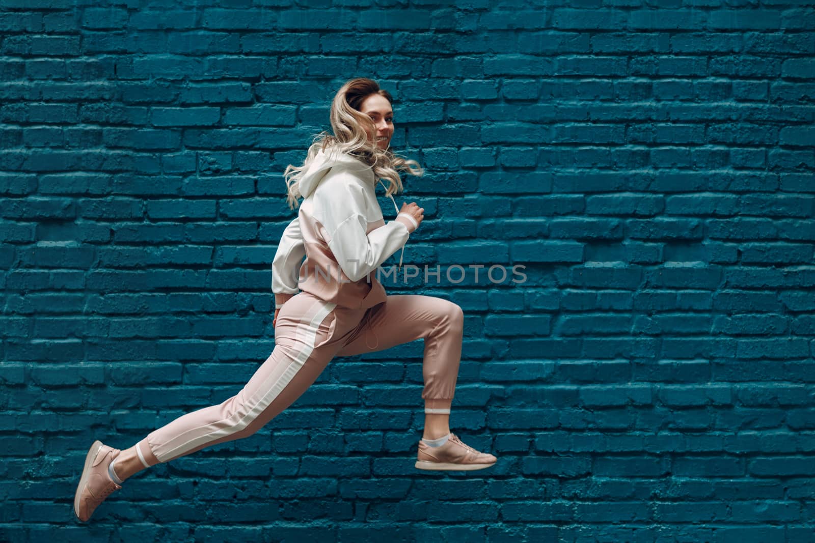 Sporty young woman in a pink sports suit. Jumping and running female.