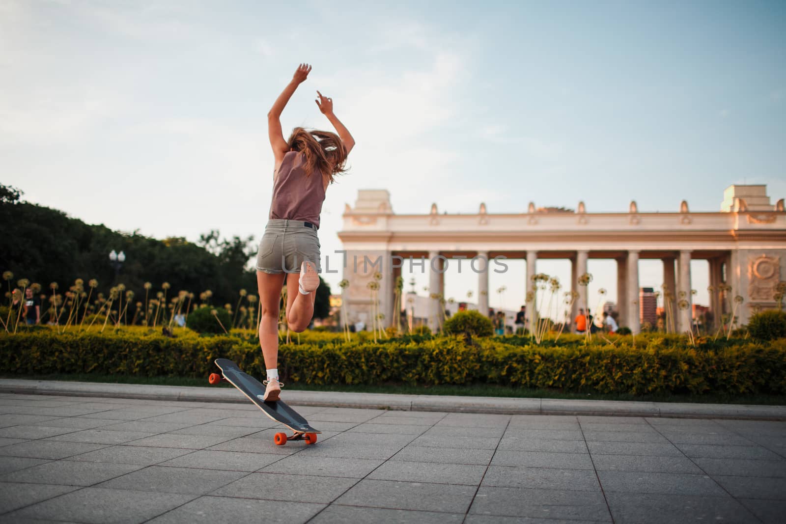 Young sporty woman riding on the longboard in the park