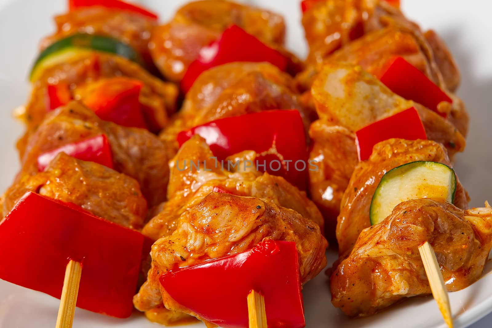raw marinated meat on wooden skewers, pork, chicken, beef in white plate on white background