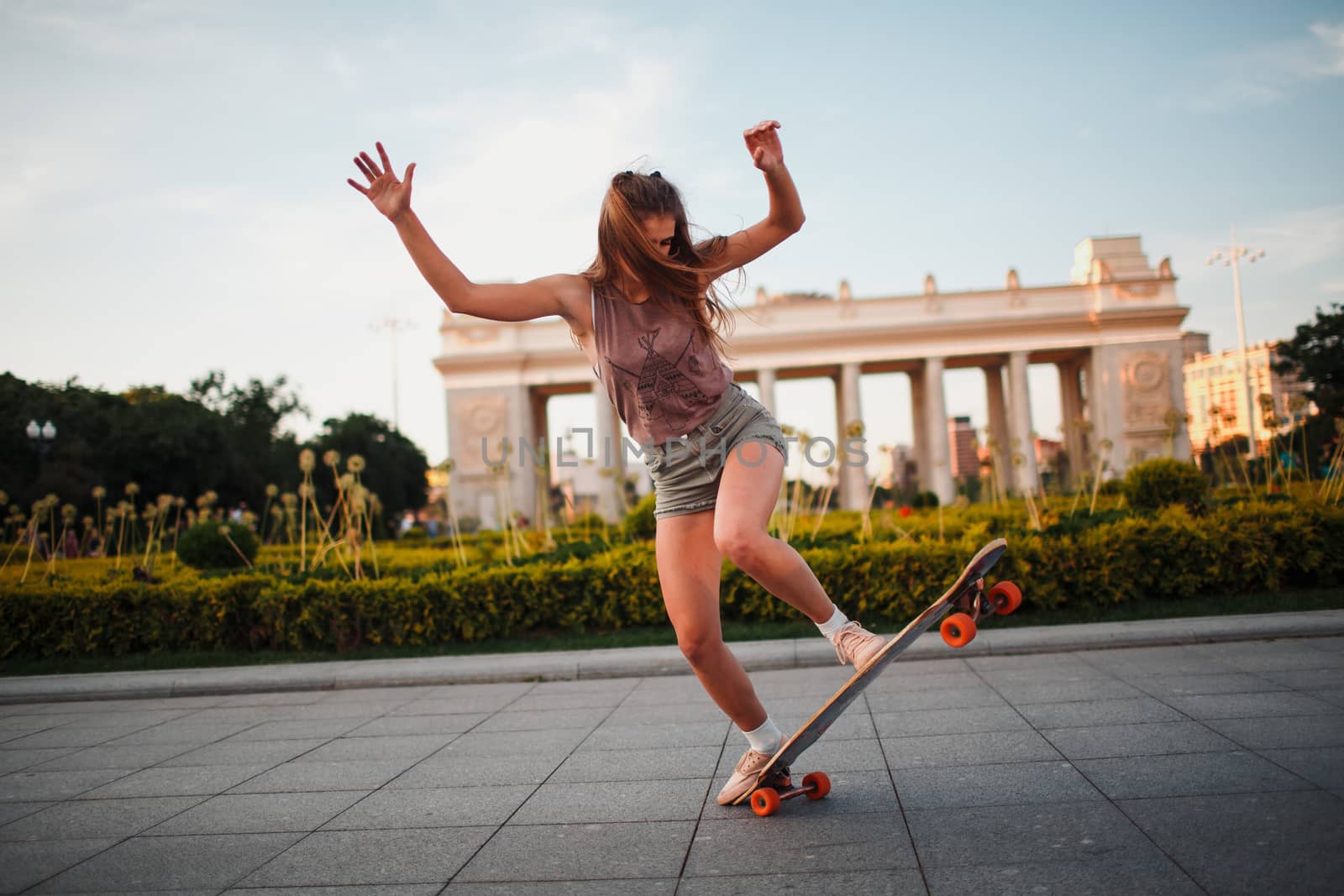Young sporty woman riding on the longboard in the park by primipil