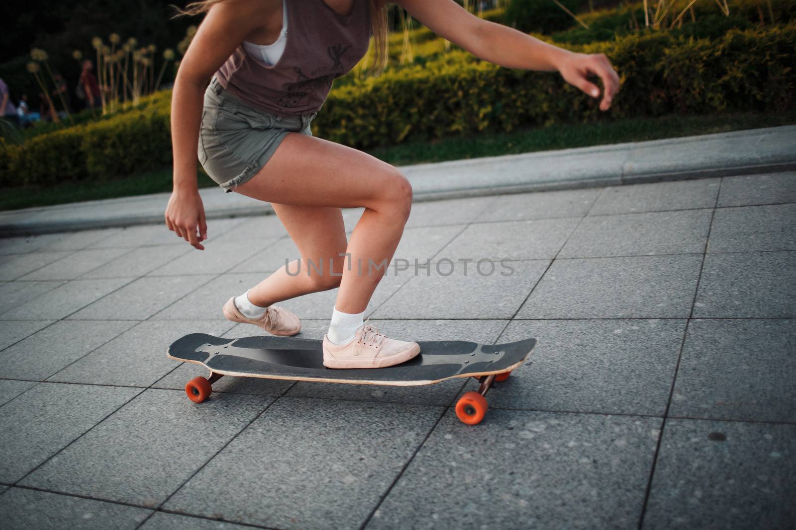 Young sporty woman riding on the longboard in the park by primipil