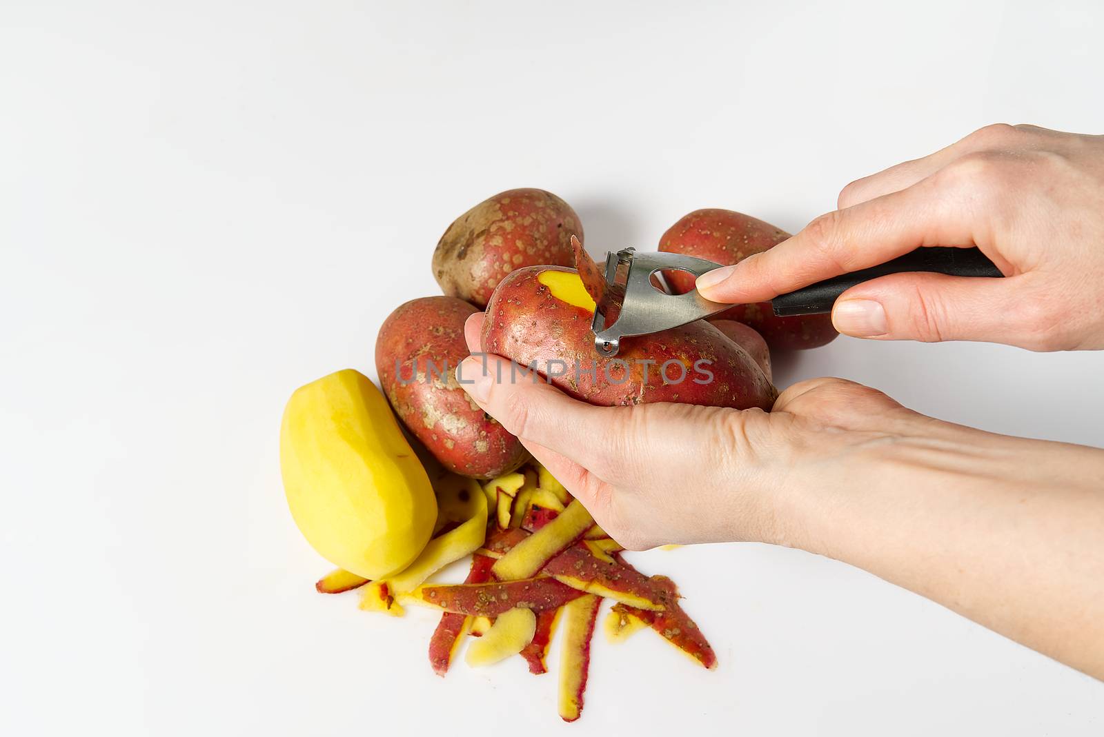 a pile of unpeeled potatoes and green potatoes peeling, white background, object isolated on white. potato and peeler