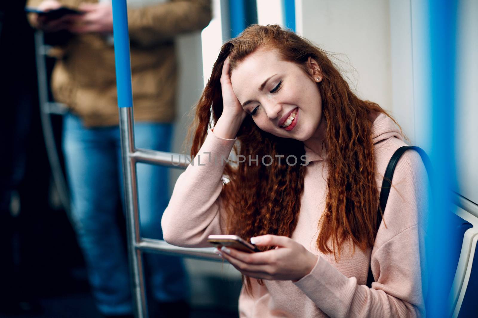 Young woman with mobile phone in subway. Wi fi in metro concept.