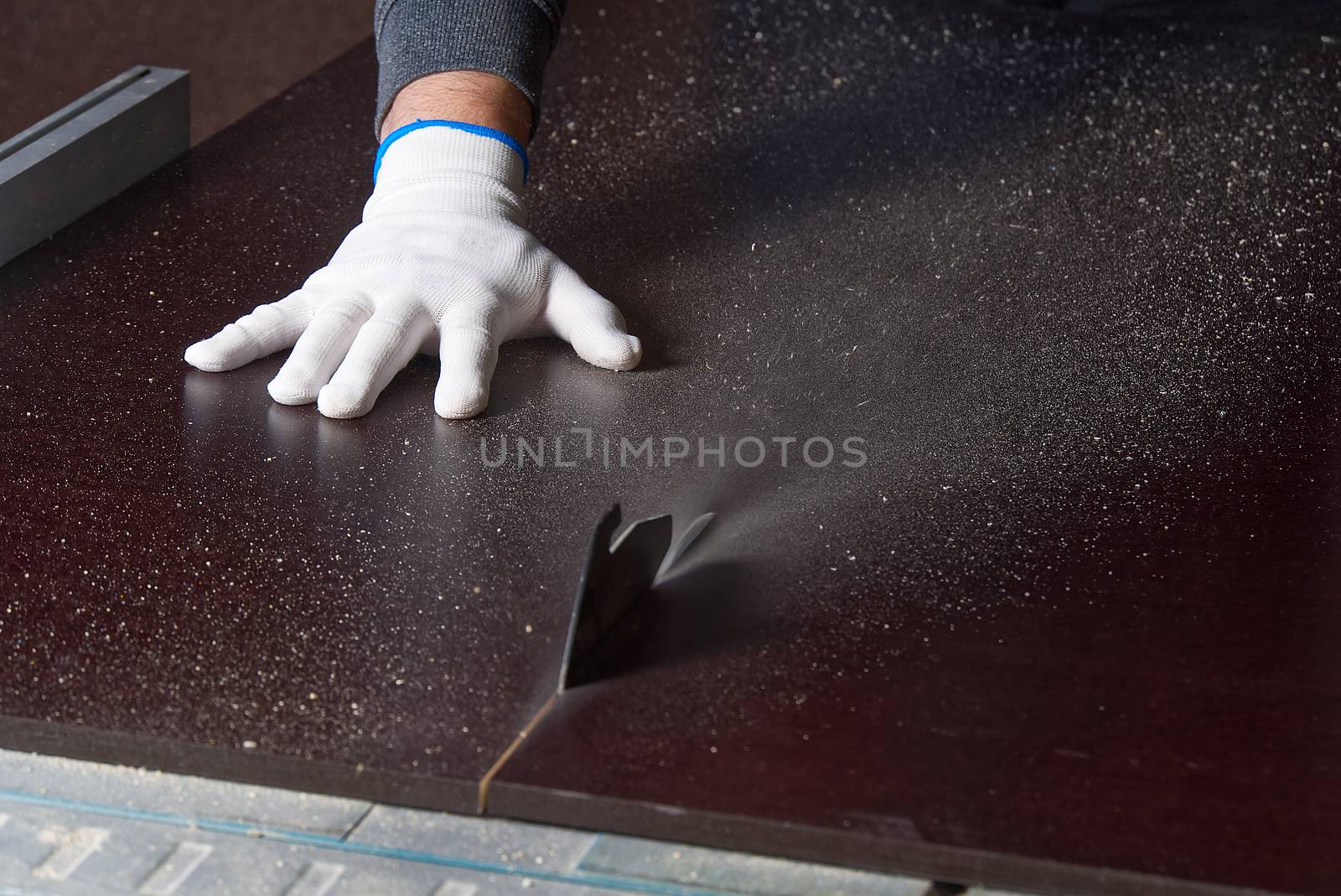 the master saws a brown building shield. master saws plywood on a circular saw. Cutting moisture-proof marine plywood.