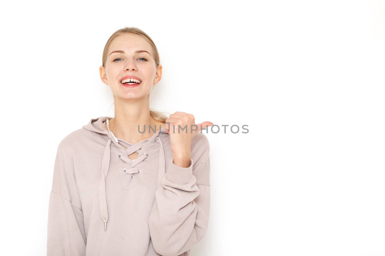 Young laughing woman pointing finger to copy space white background