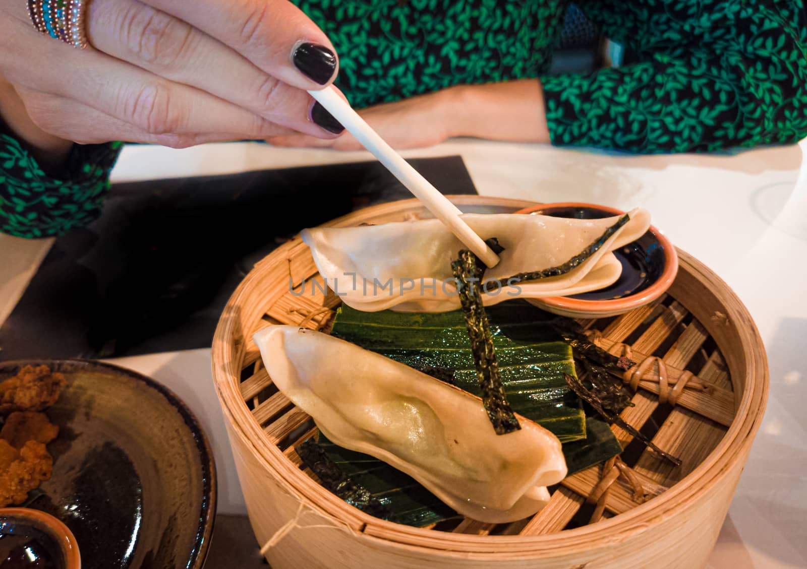 Woman hand holding japaneese gyoza with chopsticks. Japanese or asian restaurant and food