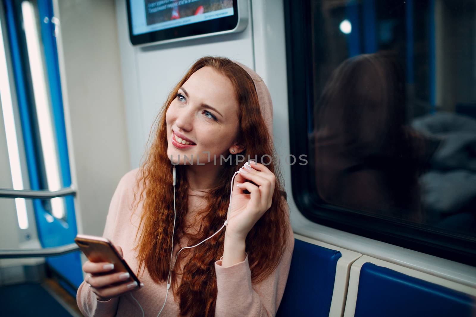 Young woman listen music with mobile phone in subway. Wi fi in metro concept.