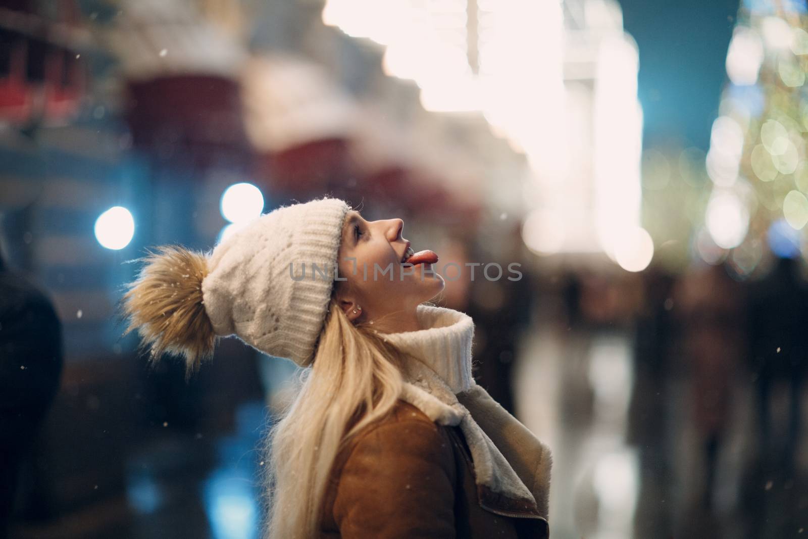 Young woman catches snowflakes by mouth tongue by primipil